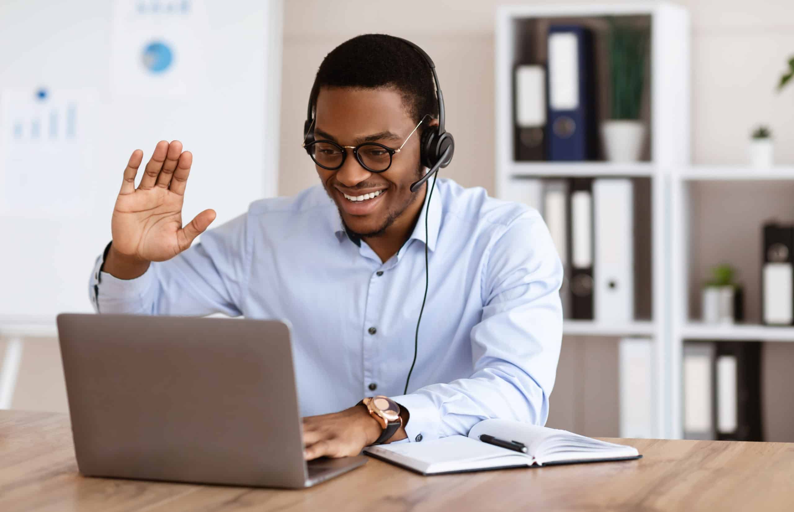 Alegre chico negro saludando a socios comerciales, con conferencia en línea
