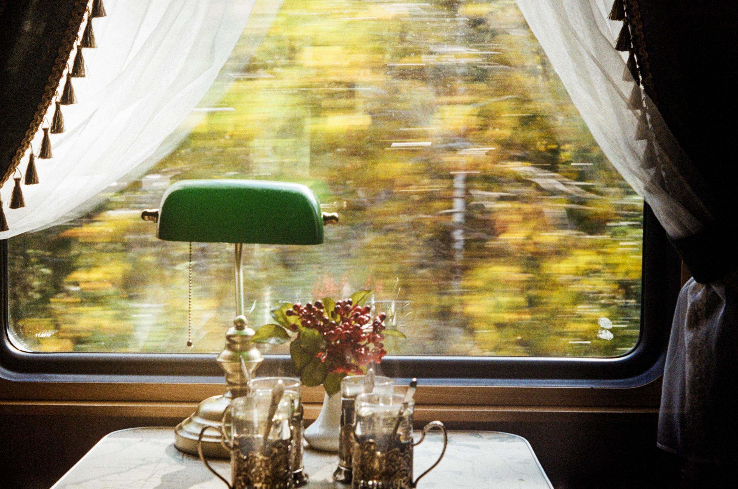 Cozy vintage train interior with elegant table setting and lush scenery outside the window Why train travel shaped modern luxury hospitality