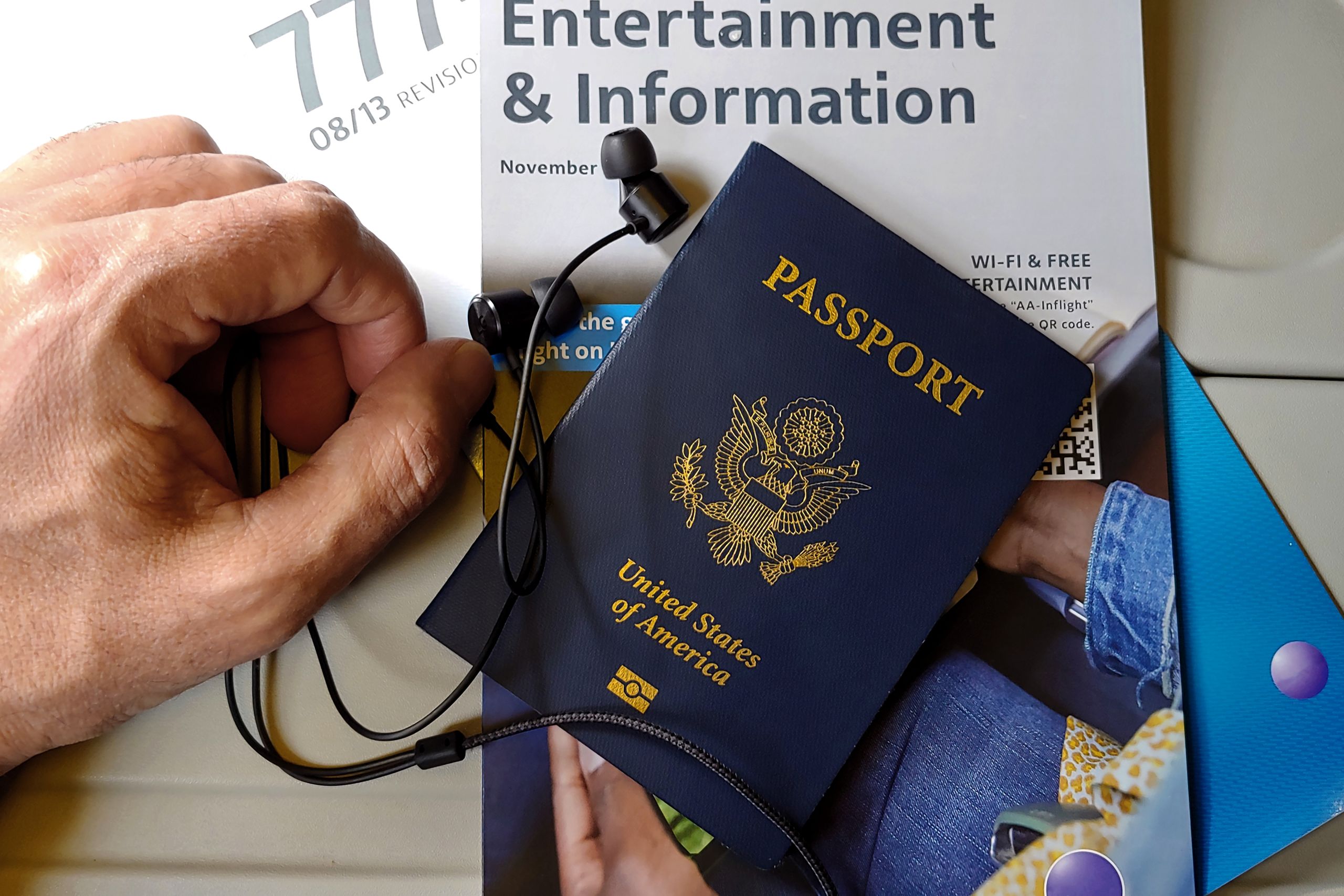 Close-up of US passport with inflight magazine and headphones on an airplane seat, ready for travel with visa