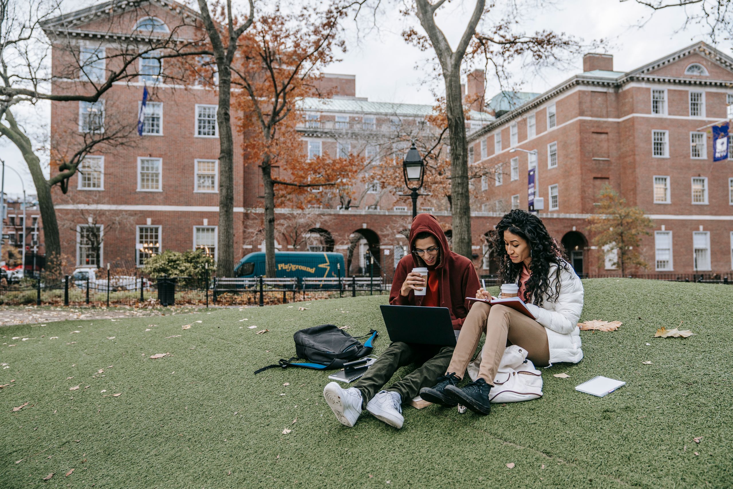 College students studying with laptops and books in a park during fall study in the us