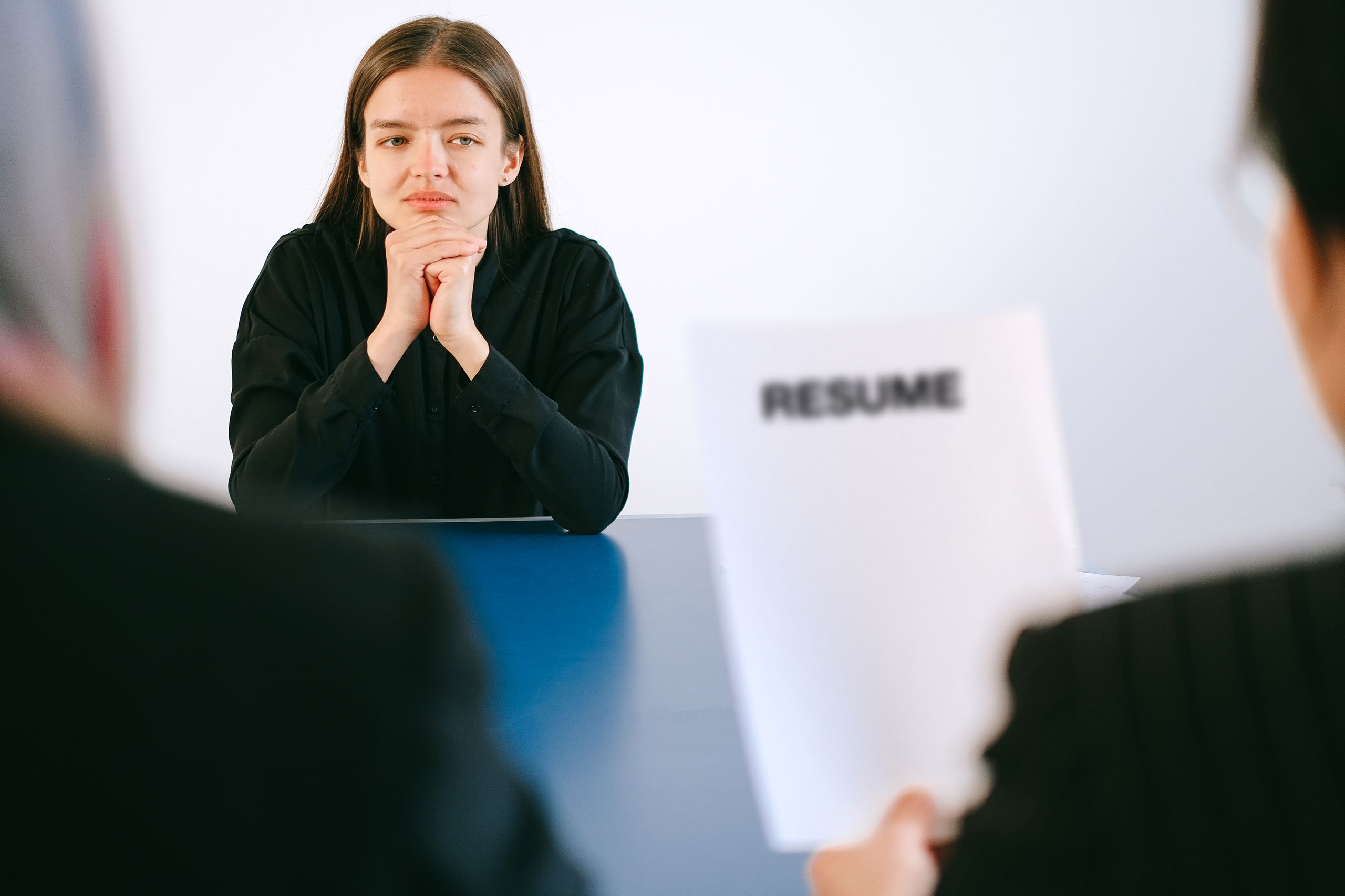 A woman in a job interview facing two employers with a focus on her resume cv.