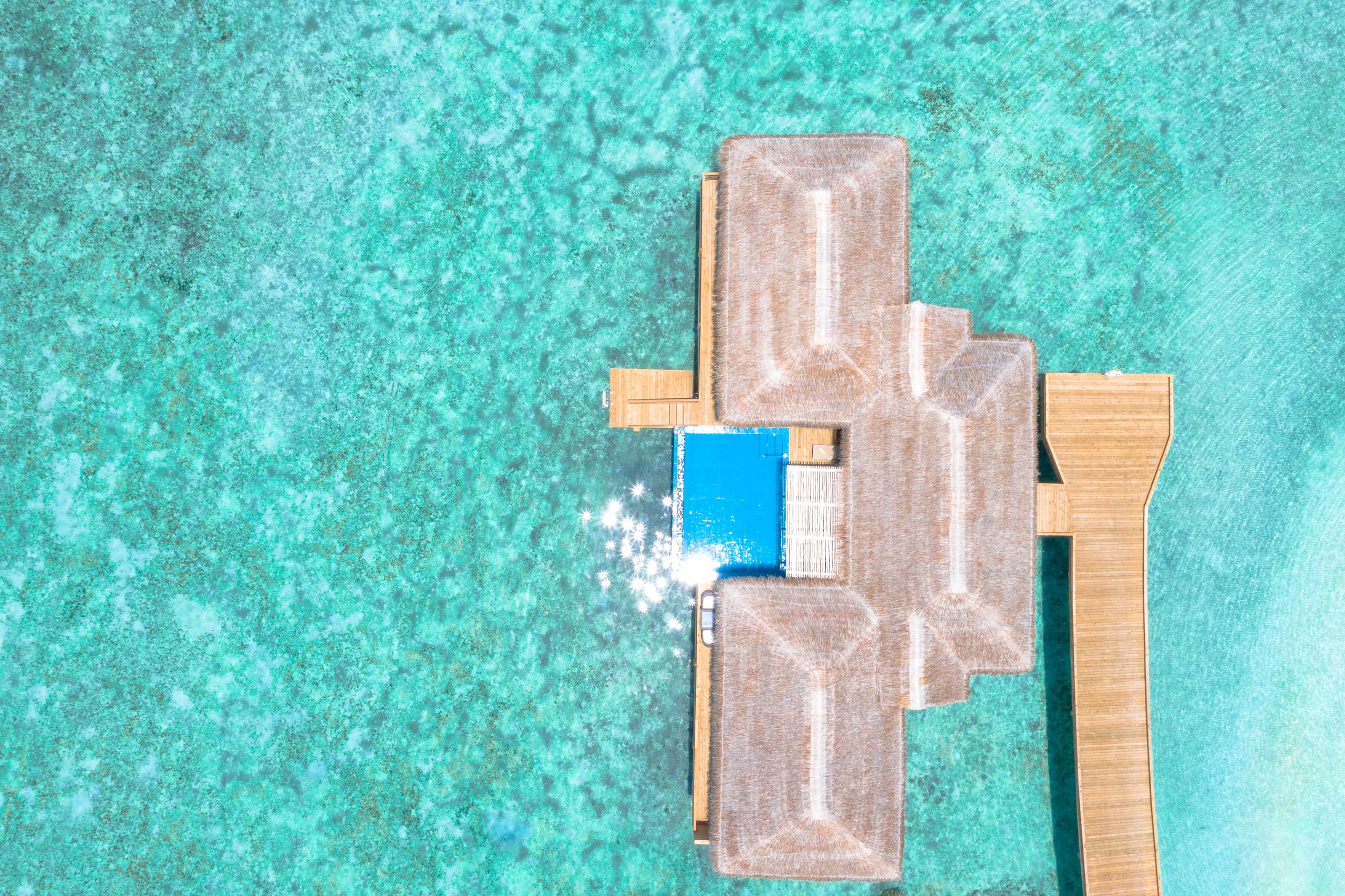 Stunning aerial view of overwater bungalows in turquoise waters, perfect for a luxury tropical getaway.
